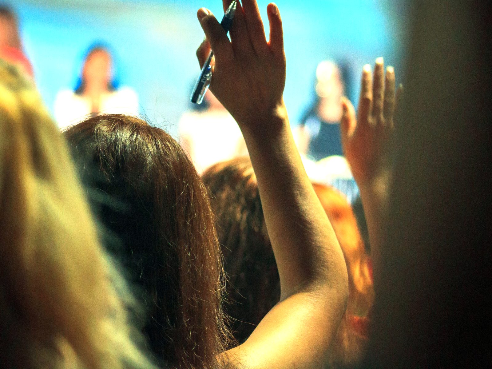 Hands raised in an audience during a presentation.